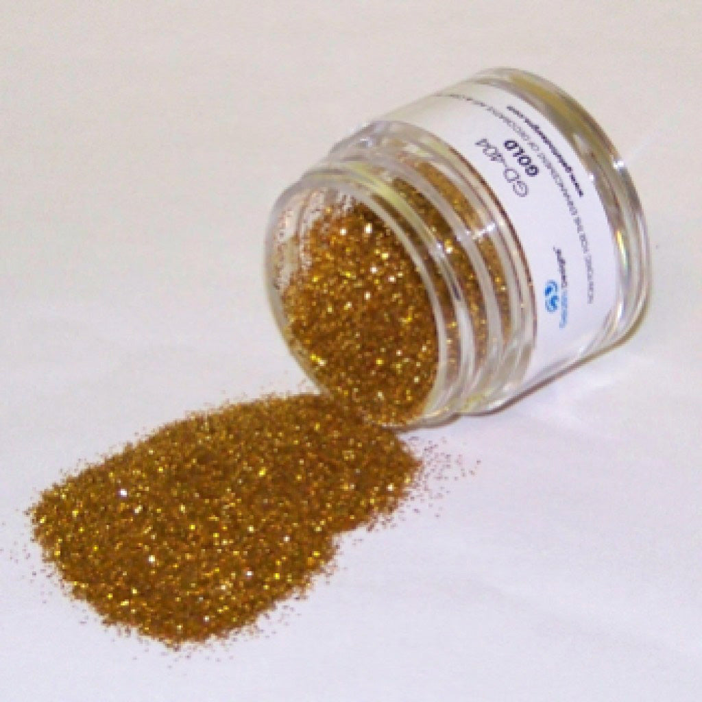 Jar of gold galaxy glitter dust tipped on its side with gold glitter spilled onto a white surface.