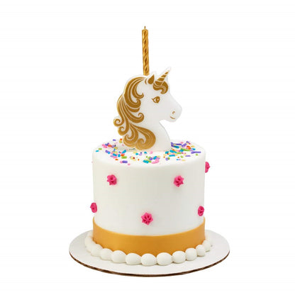 White frosted cake with colorful sprinkles and pink rosette dots, topped with a white unicorn head candle holder with gold mane and horn and a tall gold candle.
