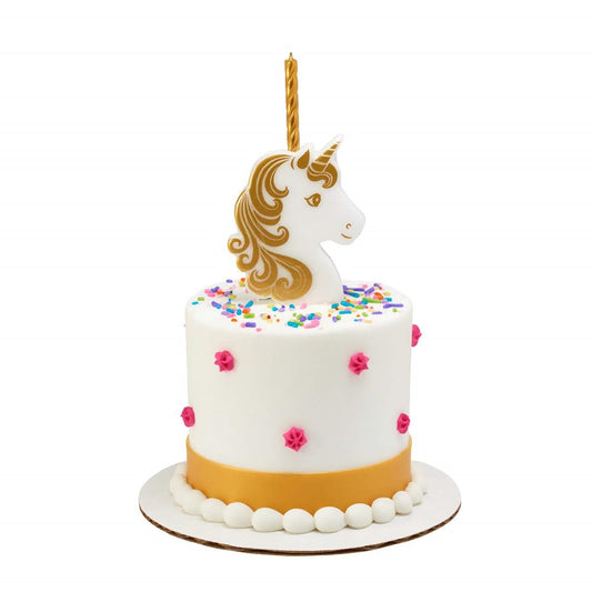 White frosted cake with colorful sprinkles and pink rosette dots, topped with a white unicorn head candle holder with gold mane and horn and a tall gold candle.
