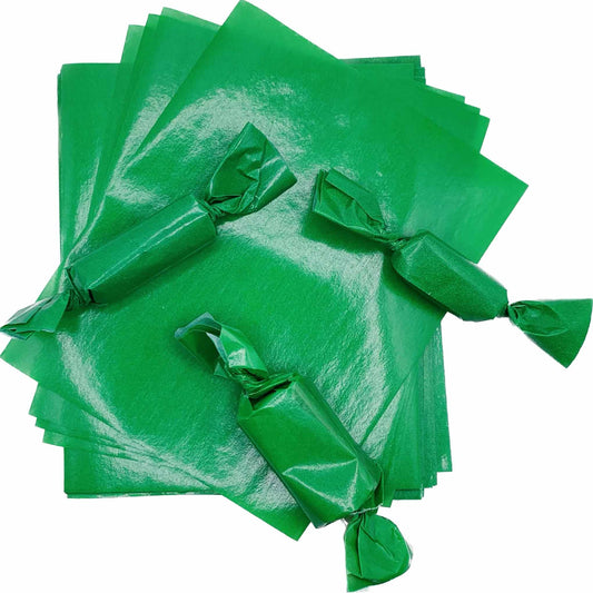 Stack of bright green 4" x 5" wax caramel wrappers with three rectangular candy pieces individually wrapped and twisted at both ends.