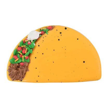 A decorated taco-shaped cookie with yellow icing, black speckles, and colorful toppings.