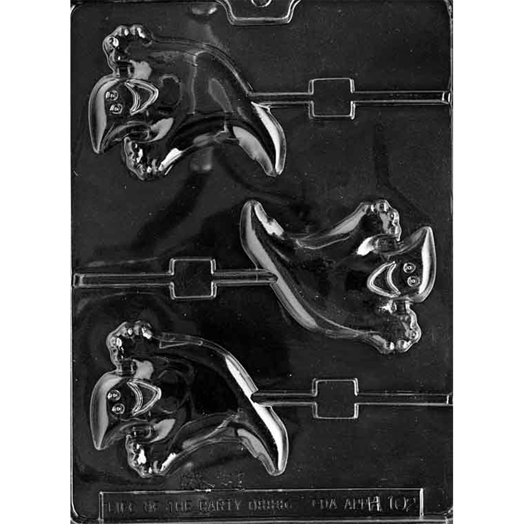 Clear plastic chocolate lollipop mold photographed on a dark background with three smiling ghost-shaped cavities, each with a built-in stick channel and a friendly face.
