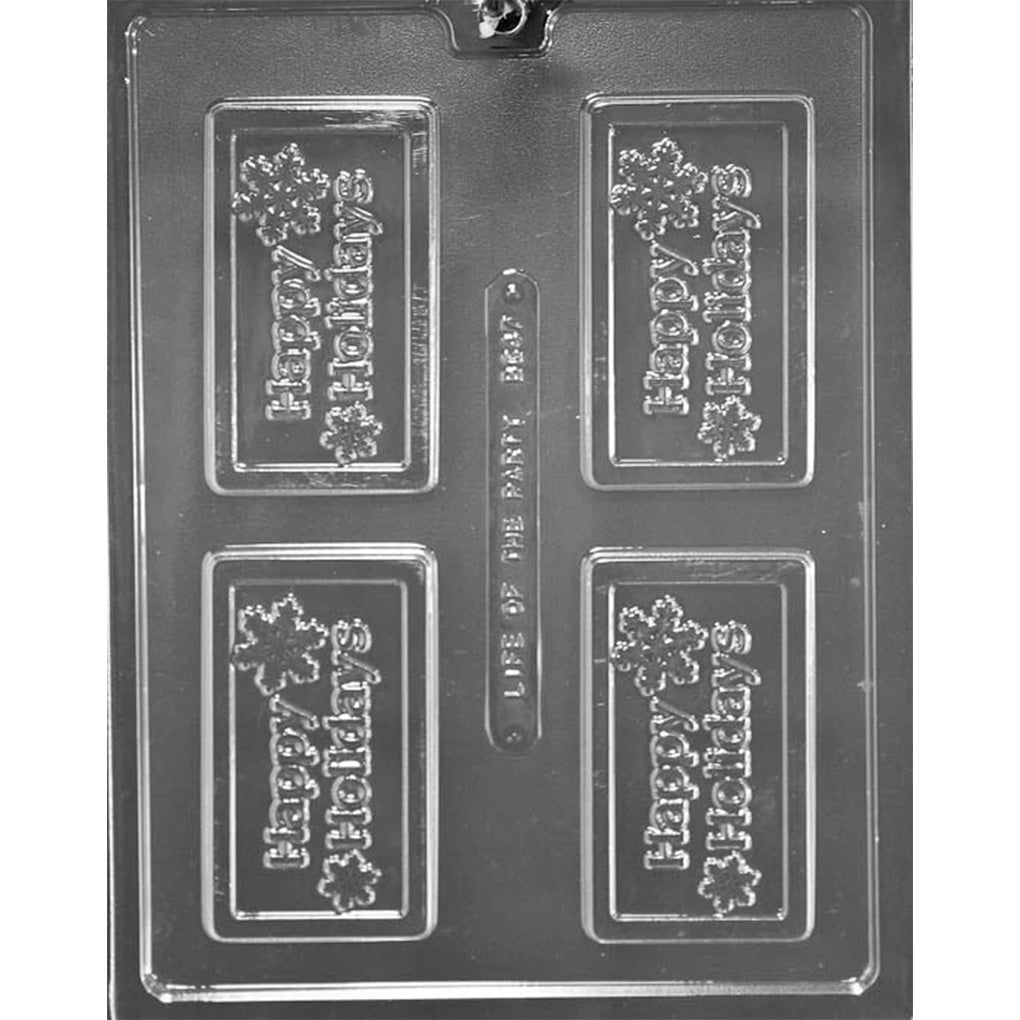 Clear plastic chocolate bar mold photographed on a dark background with four rectangular cavities, each reading “Happy Holidays” with small snowflake accents.