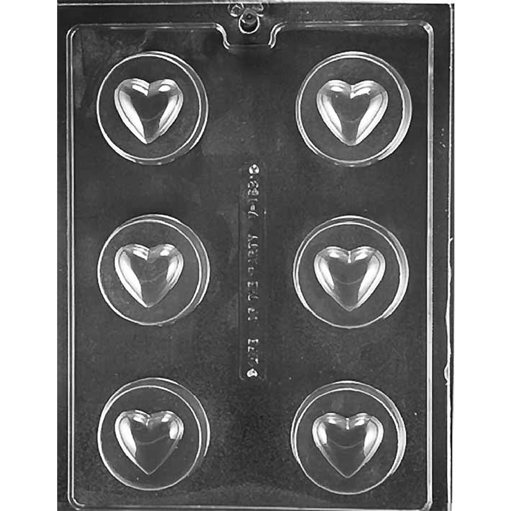 Clear plastic chocolate mold with six round cavities, each featuring a raised heart center inside a circular border, arranged in two columns on a dark background.