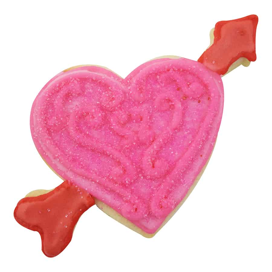 Pink heart cookie with an arrow, covered in sparkly sugar and intricate icing designs.