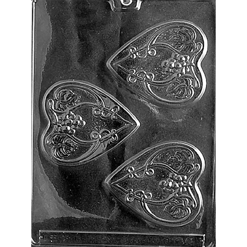 Clear Hearts with Grape Vines Chocolate Mold photographed against a black background with three heart-shaped cavities featuring curling vine, grape cluster, and rose details.