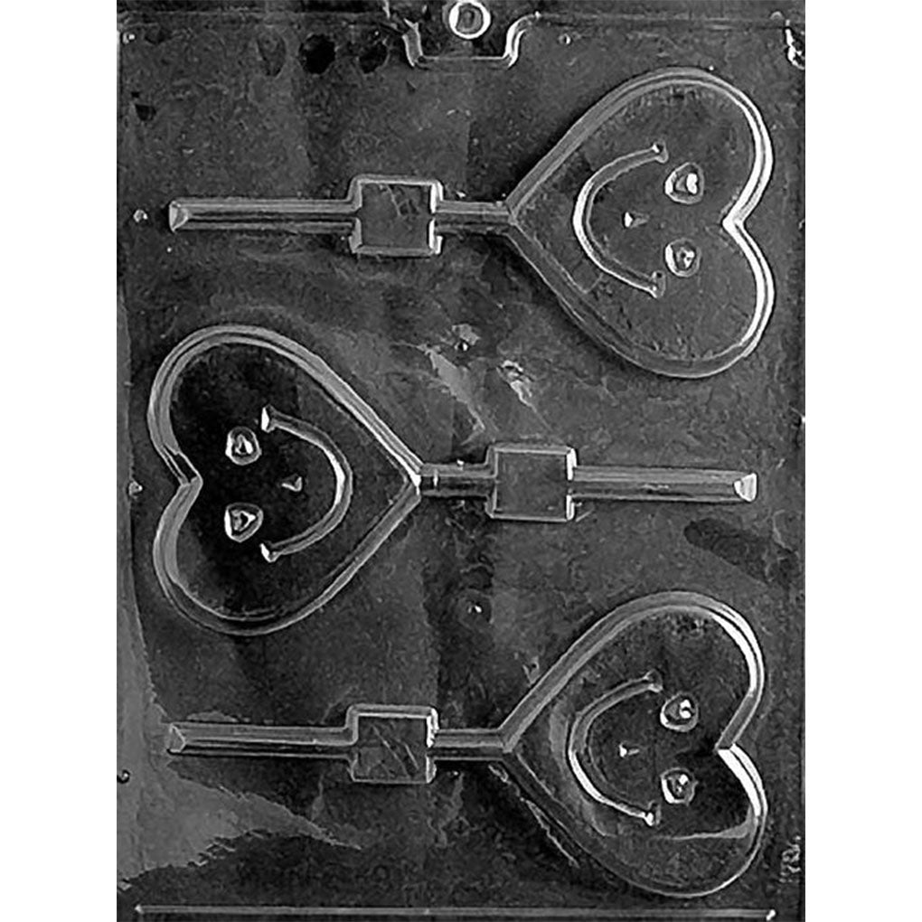 Clear plastic chocolate lollipop mold with three heart-shaped cavities, each featuring a smiling face in the center.