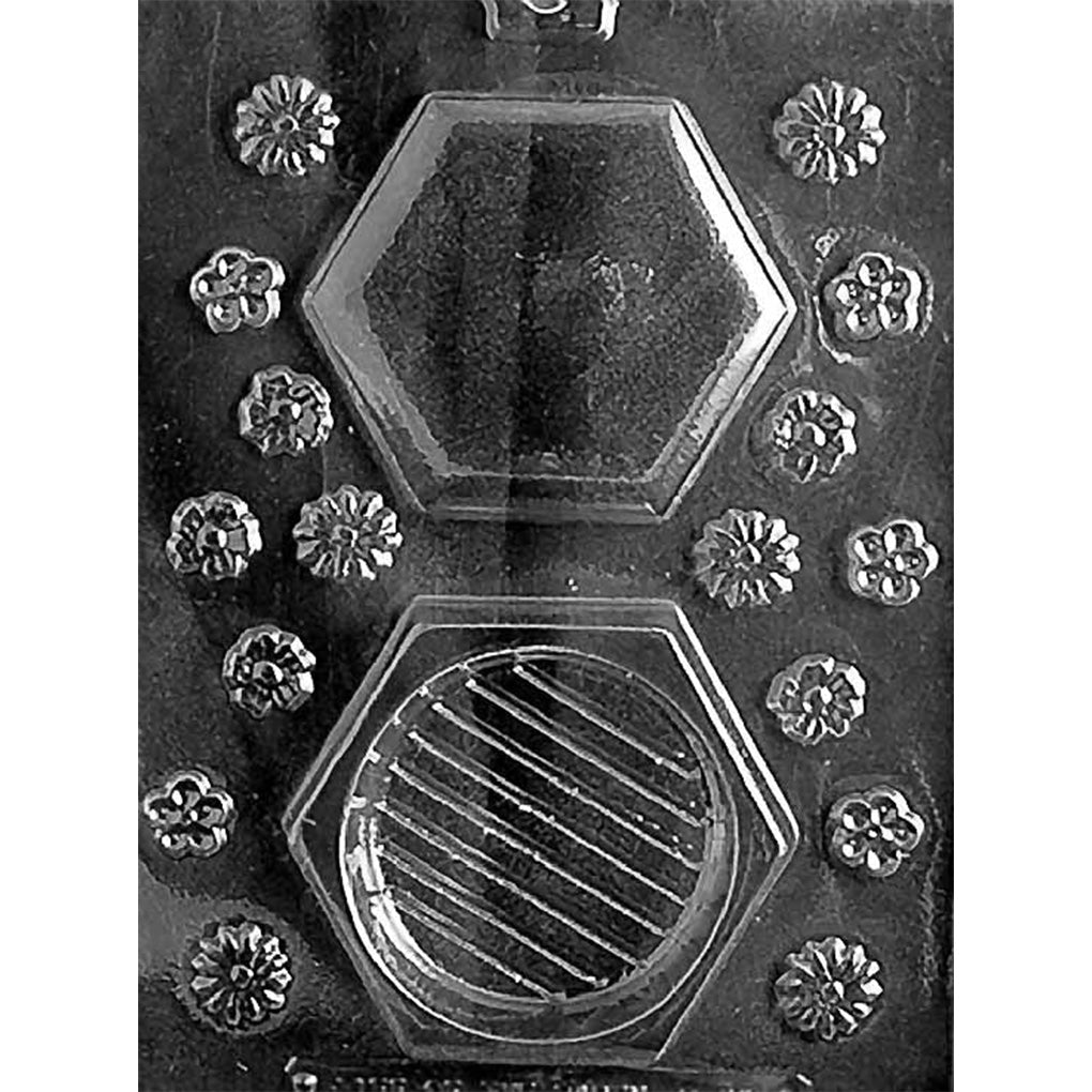Clear plastic chocolate mold photographed on a black background with two large hexagon cavities and multiple small flower-shaped cavities arranged around them.