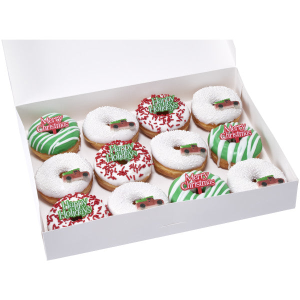 White bakery box filled with a dozen decorated donuts, each topped with green or red holiday picks and festive decorations.