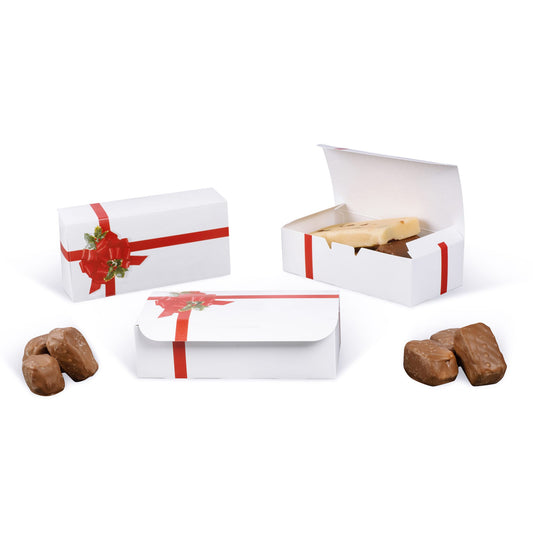 White candy boxes with a red ribbon and holly bow design shown closed and open on a white background, with an open box holding a slab of candy and chocolates nearby.