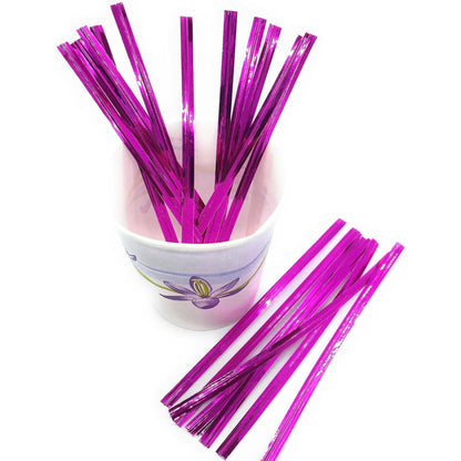 Bright purple metallic twist ties standing in a small paper cup, with additional purple ties stacked nearby on a white background.