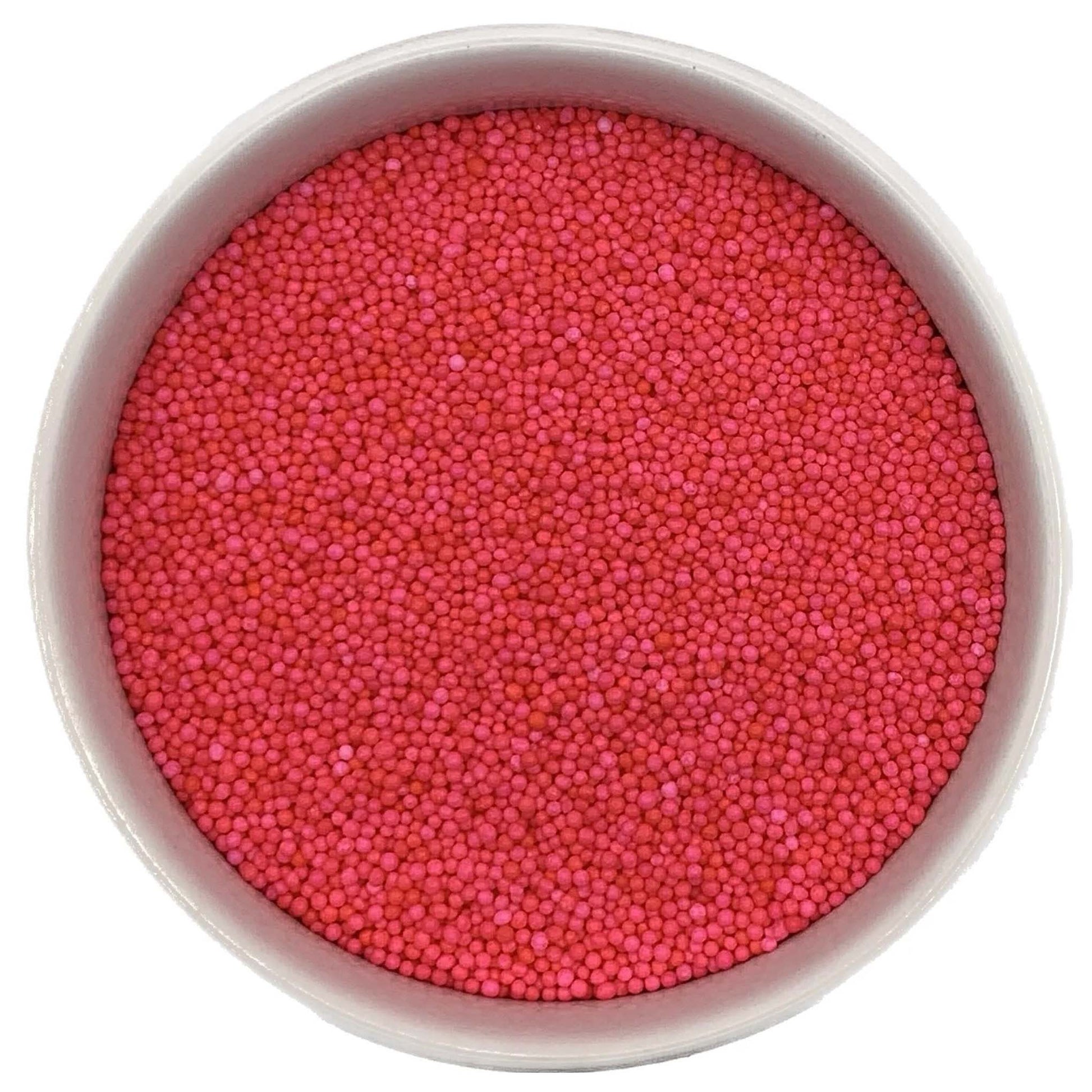 Top-down view of a white bowl filled with hot pink non-pareils, showing tiny round sprinkle beads in bright fuchsia and pink shades.