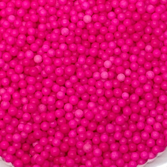 Close-up of 4mm hot pink sugar pearls in a clustered pile, ideal for decorating cakes, cupcakes, and cookies.