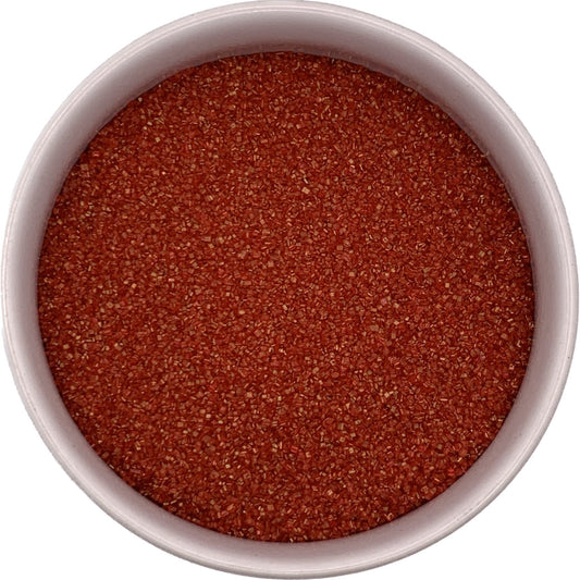 Red sanding sugar close-up in a clear container, vibrant ruby crystals great for holiday and Valentine bakes.