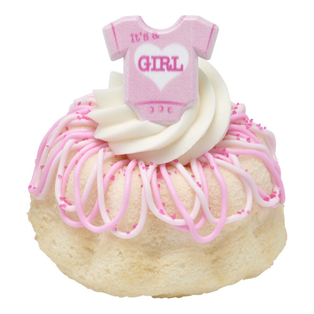 Mini cake topped with piped frosting and a pink "It's a Girl" onesie ring for baby shower decorating