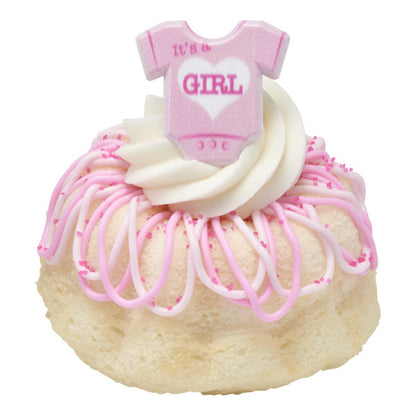 Mini cake topped with piped frosting and a pink "It's a Girl" onesie ring for baby shower decorating