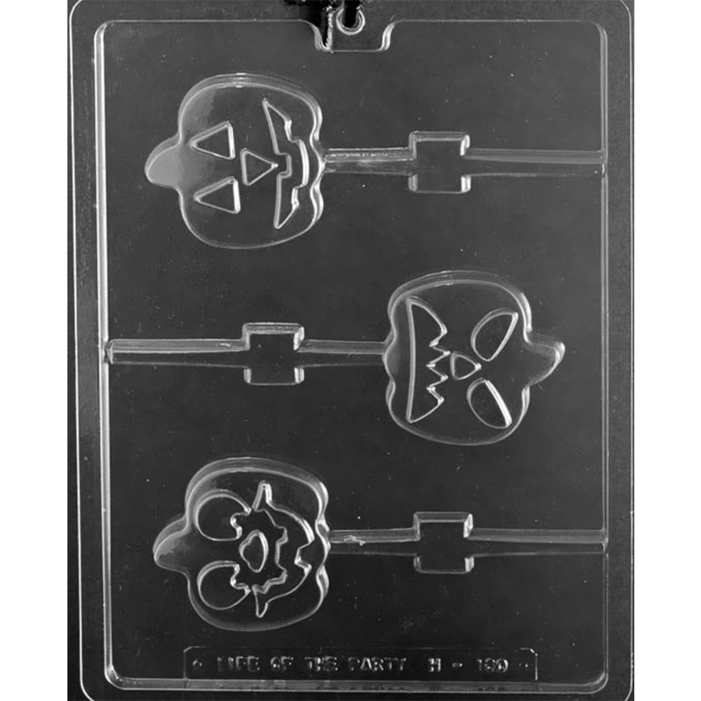 Clear plastic pumpkin face chocolate lollipop mold photographed on a dark background, showing three jack-o'-lantern pop cavities with different carved face expressions and built-in stick channels.