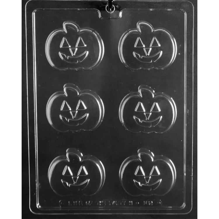Clear plastic jack-o-lantern chocolate mold photographed on a black background with six pumpkin cavities, each showing triangle eyes and a smiling carved mouth.