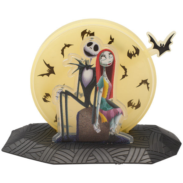 Jack and Sally cake topper sitting in front of a yellow moon with flying black bats, from The Nightmare Before Christmas.