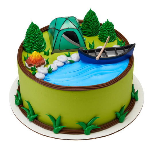 A vibrant camping-themed cake with a green fondant exterior and detailed sugar art decorations, featuring a blue fondant river, a gray canoe with paddle, green trees, a campfire with flames, and a teal camping tent on top, ideal for outdoor enthusiasts and celebratory events.