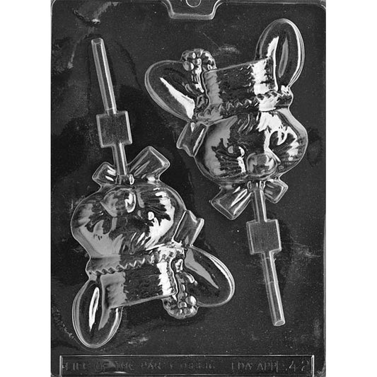 Clear plastic chocolate lollipop mold with two large lady bunny cavities, each showing a rabbit wearing a wide-brim hat and neck bow, with a built-in stick slot on a dark background.
