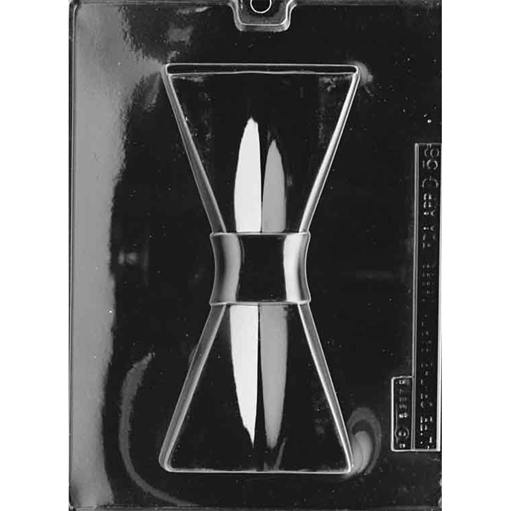Clear plastic chocolate mold photographed on a black background with one large bow tie-shaped cavity, including a raised center band and wide tapered ends.