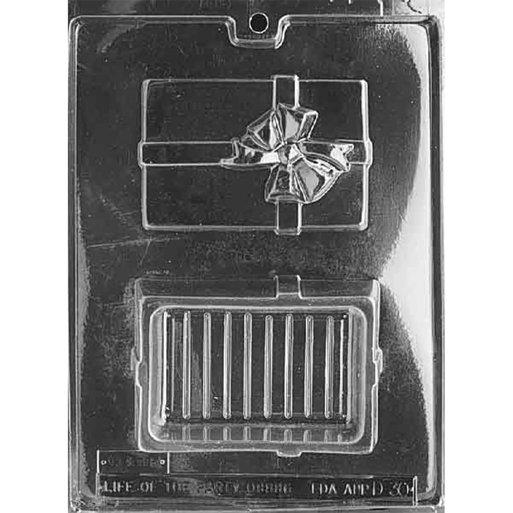 Clear plastic chocolate pour box mold with two cavities: a gift box lid featuring a raised ribbon and bow, and a matching rectangular base cavity for filled chocolates.