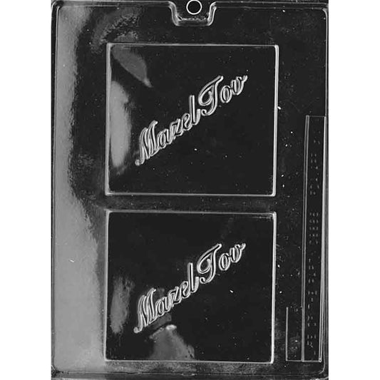 Clear plastic chocolate mold with two large square cavities, each embossed with the words “Mazel Tov” in flowing script; shown on a dark background for contrast.