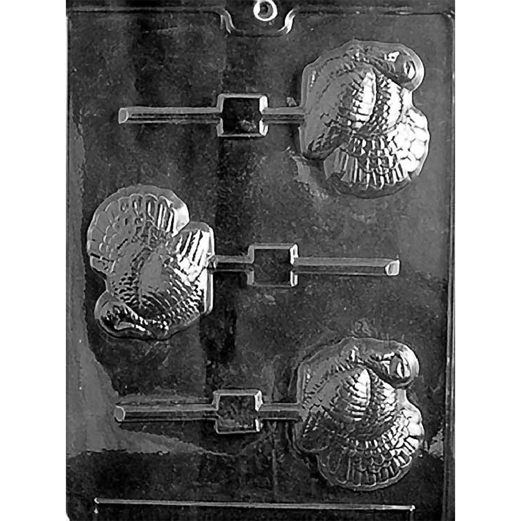 Clear Large Turkey Chocolate Lollipop Mold photographed against a black background with three turkey-shaped cavities featuring detailed feathers and built-in stick channels.