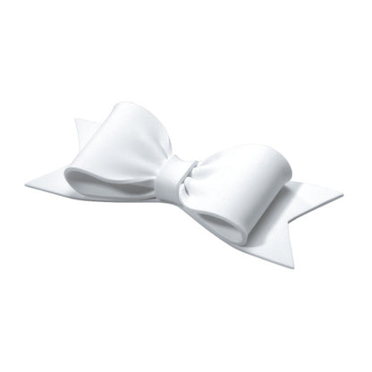 Angled view of a sculpted white gum paste bow showing three-dimensional curves and ribbon tails.