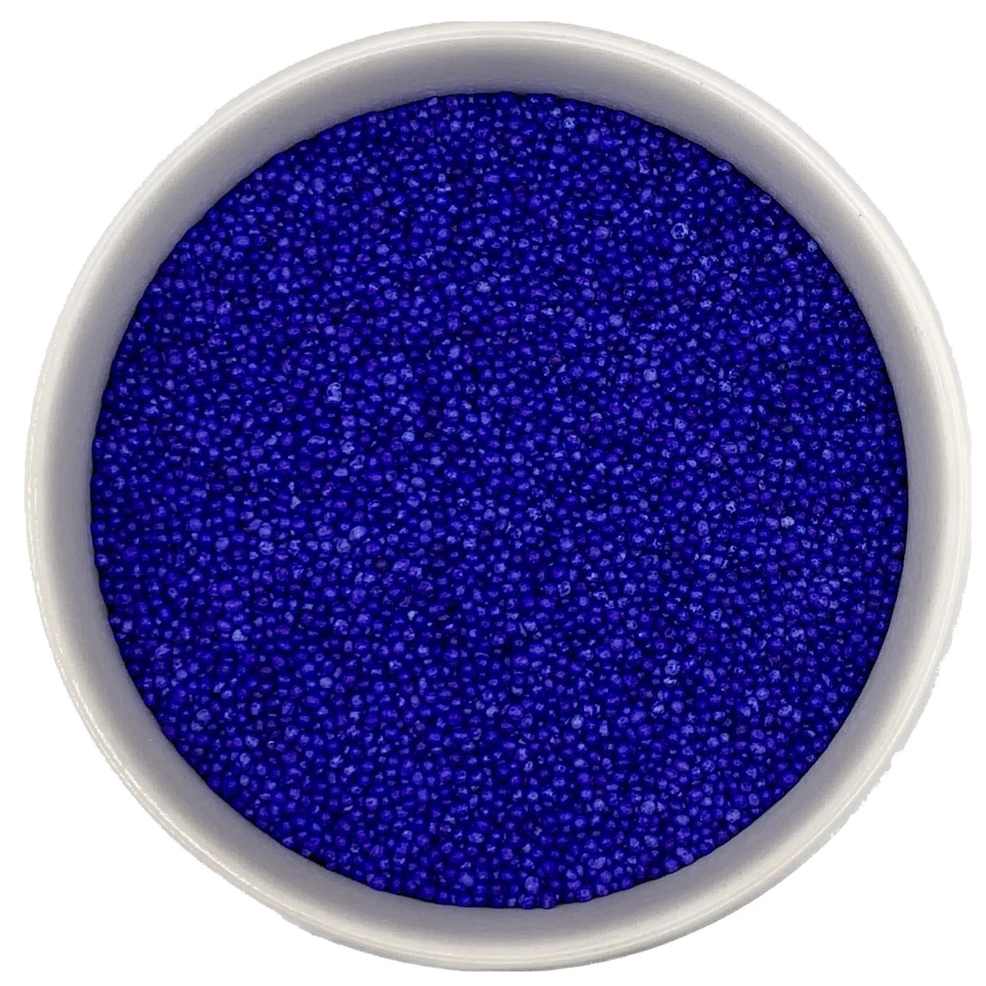 Top-down view of a white bowl filled with lavender non-pareils, showing tiny round sprinkle beads in a vivid blue-violet lavender shade.