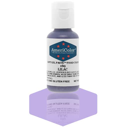 A bottle of AmeriColor Lilac soft gel paste food coloring with a white cap, blue label, and red stars, positioned on a soft lilac reflective surface with the bottle’s reflection clearly visible.