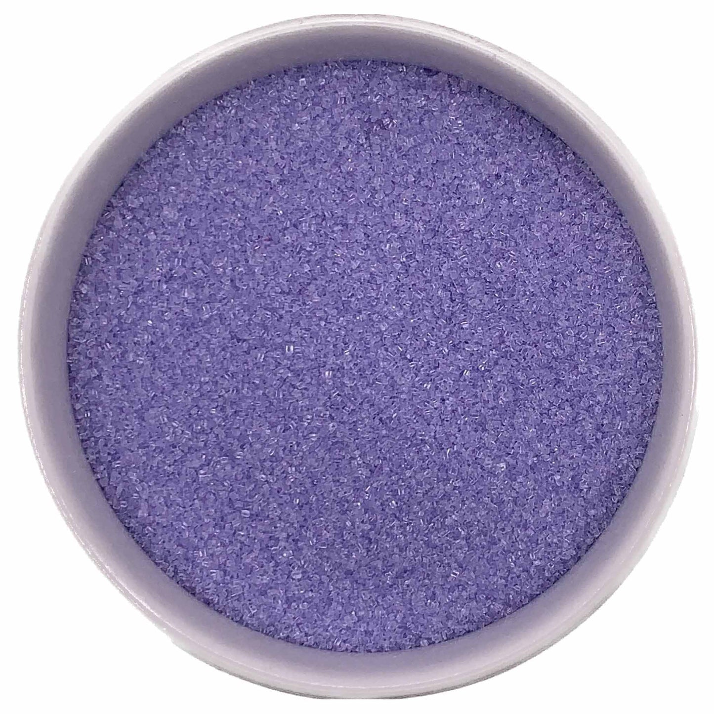 Top-down view of a white bowl filled with lilac fine sanding sugar, showing tiny pastel purple crystals with a soft sparkling texture.