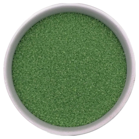 Lime green fine sanding sugar crystals in a white bowl on a white background.