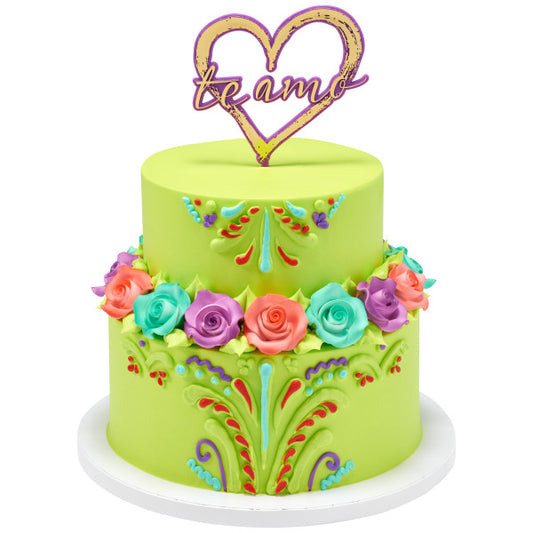 Lime green two-tier cake with colorful florals and a red "Te Amo" heart cake topper.