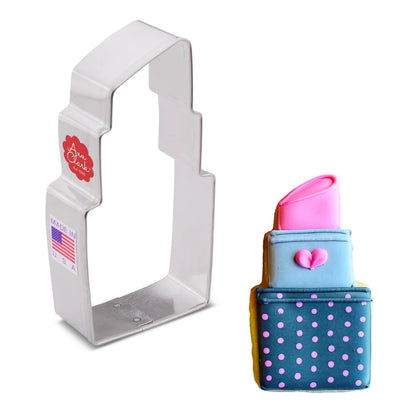 Lipstick cookie cutter next to a decorated lipstick-shaped cookie with pink icing and polka dot details.