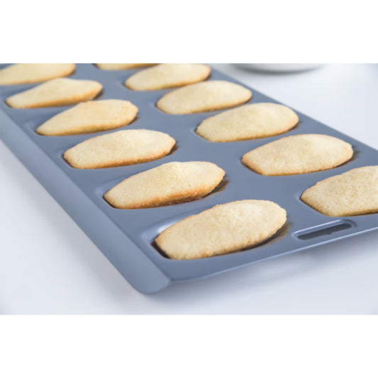 Madeleine pan filled with golden baked madeleines, fresh from the oven, showing uniform shape and texture.