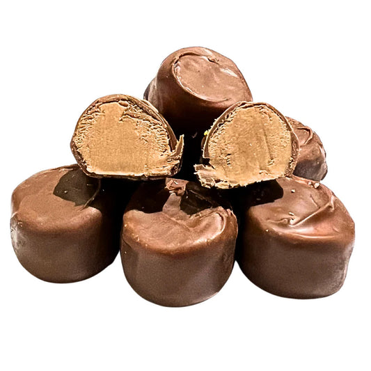 Stack of round maple-filled chocolates, with two cut open to reveal a creamy maple candy center coated in smooth milk chocolate.