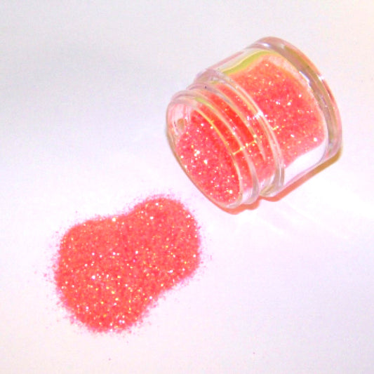 Small clear jar tipped on its side spilling Miami orange glitter dust onto a white surface, showing fine bright orange sparkling particles with warm iridescent shine.