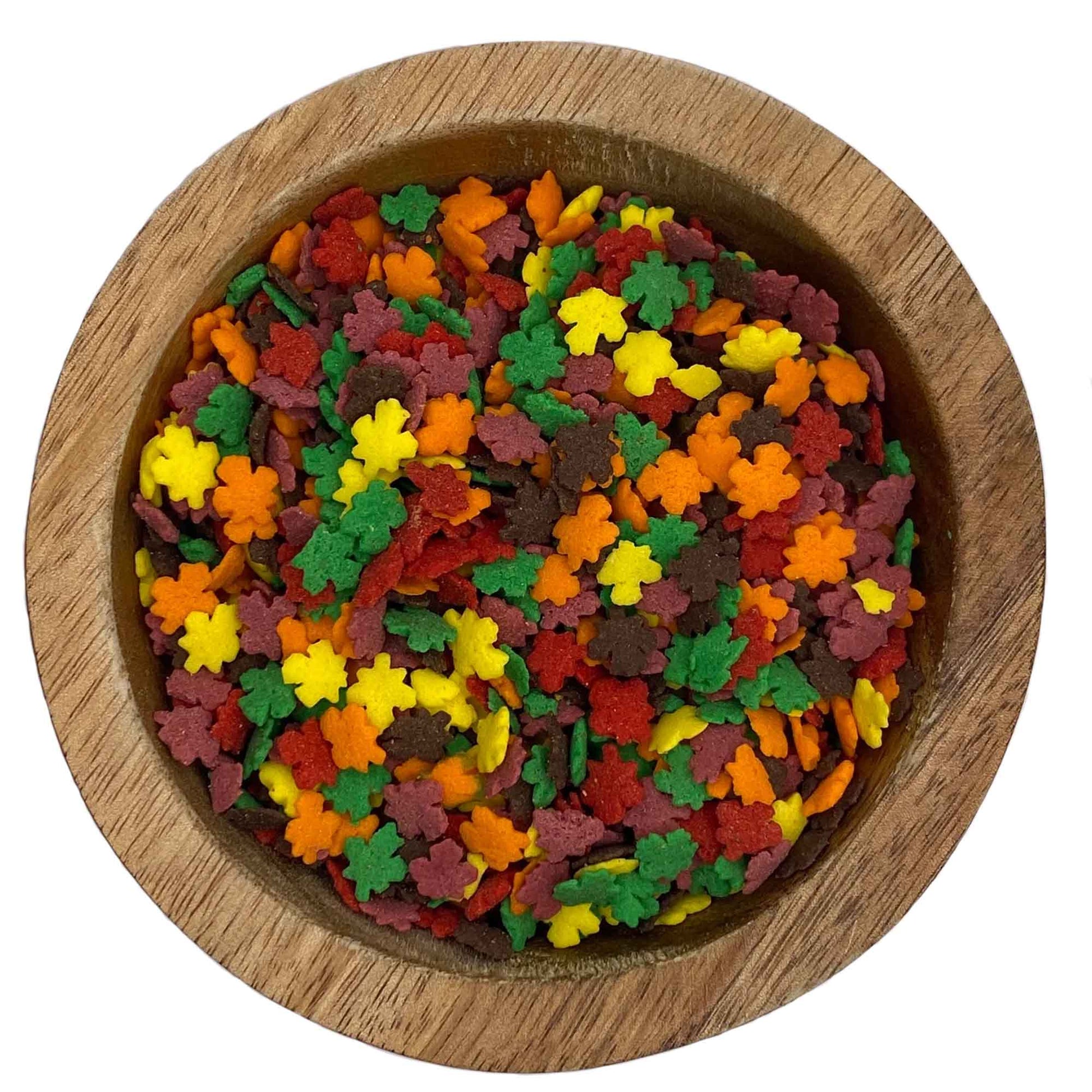 Close-up of mini autumn leaf quins sprinkles in red, orange, yellow, and brown, packaged in a 4 oz container.