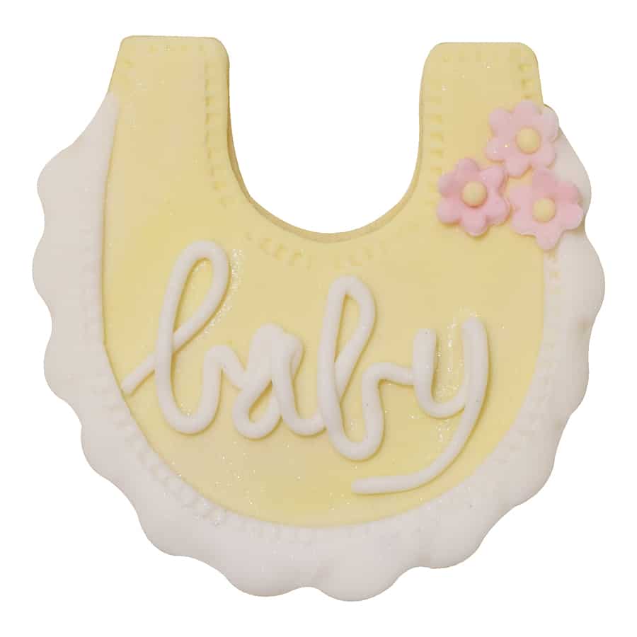 Decorated baby bib-shaped cookie with yellow icing, white trim, pink flowers, and "baby" written in script.