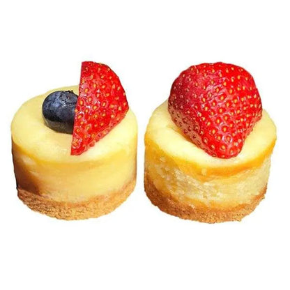 Two plain mini cheesecakes topped with fresh strawberry and blueberry.