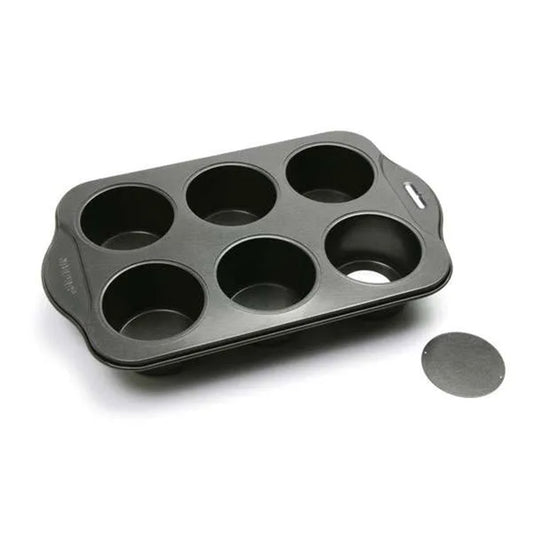 Empty six-cavity mini cheesecake pan photographed on a white background with one round removable bottom disk placed beside the pan.