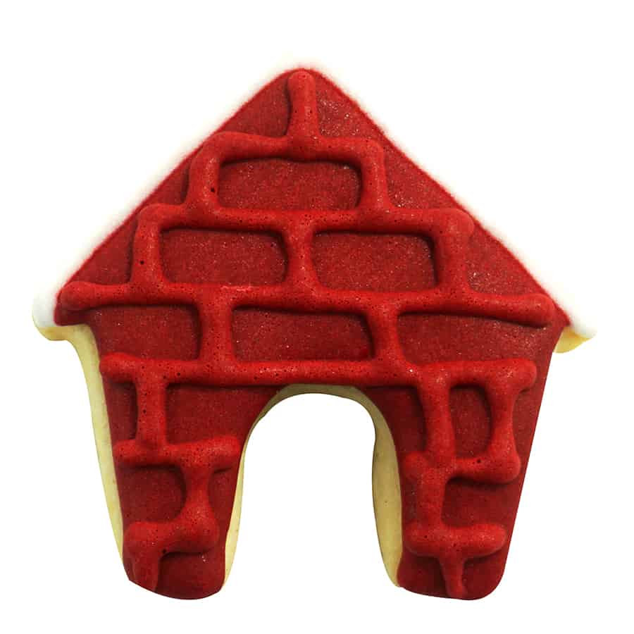 Decorated doghouse-shaped cookie with red brick-patterned icing and a white roof, made using the Mini Dog House Cookie Cutter.