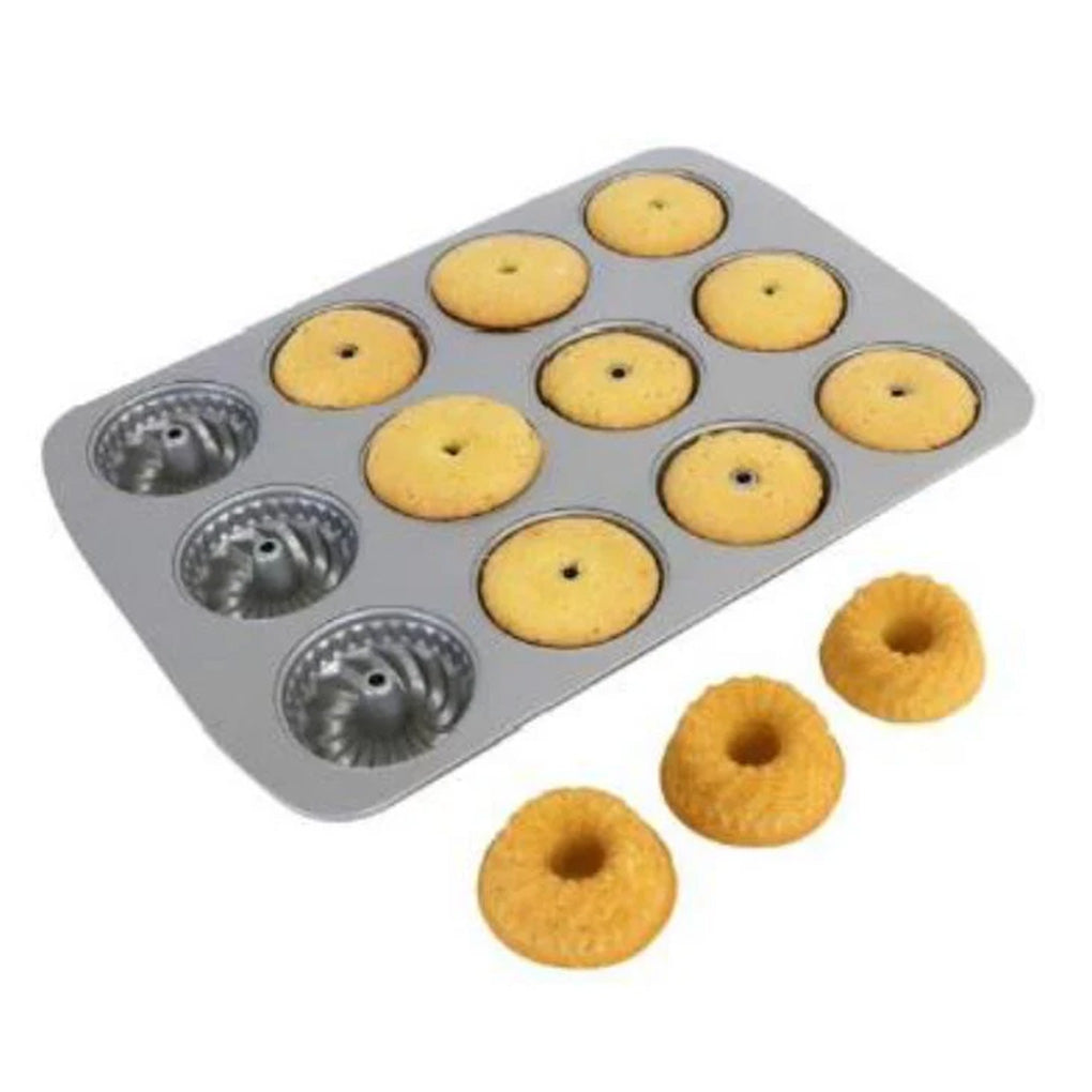 12-cavity mini fluted ring pan showing several baked mini ring cakes in the pan, with three finished mini cakes placed in front on a white background.