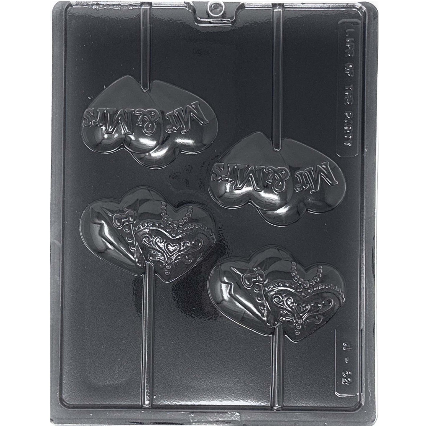 Clear Mr & Mrs wedding chocolate lollipop mold photographed against a black background, with four heart-shaped cavities featuring raised Mr & Mrs lettering and tuxedo and ornate wedding dress designs.