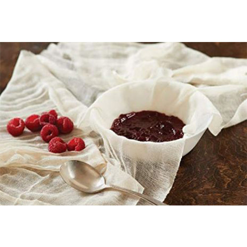Cheesecloth draped over a bowl filled with raspberry jam, fresh raspberries and a spoon beside it on a wooden table.