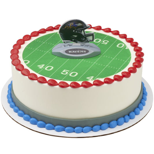A round cake decorated with a green football field print, red piped border, blue and gray base accents, and a Baltimore Ravens helmet topper on top.