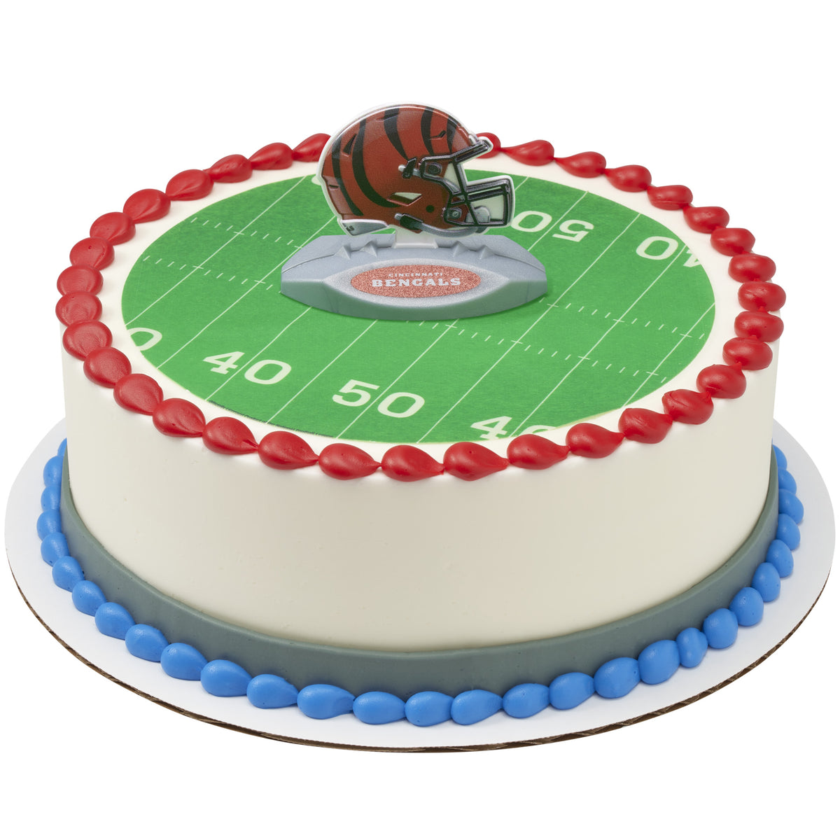 A round cake decorated with a Cincinnati Bengals theme, featuring a green football field print with white yard lines, a red piped border, blue and gray base accents, and a helmet topper on top.