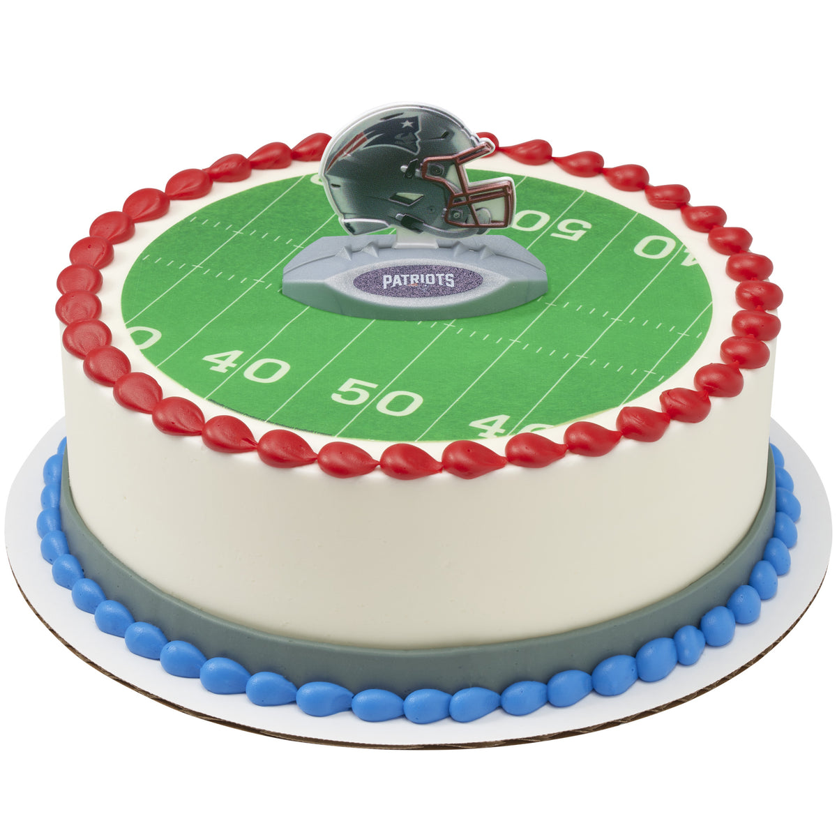 A round cake decorated with a green football field print, red piped border, blue base border, and a helmet topper on top. The side of the cake is white, and the helmet topper has 'PATRIOTS' on it.